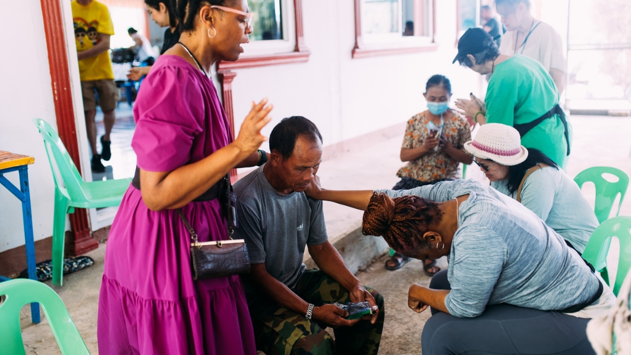 Mission trip team praying with a local man during Christian missions outreach.