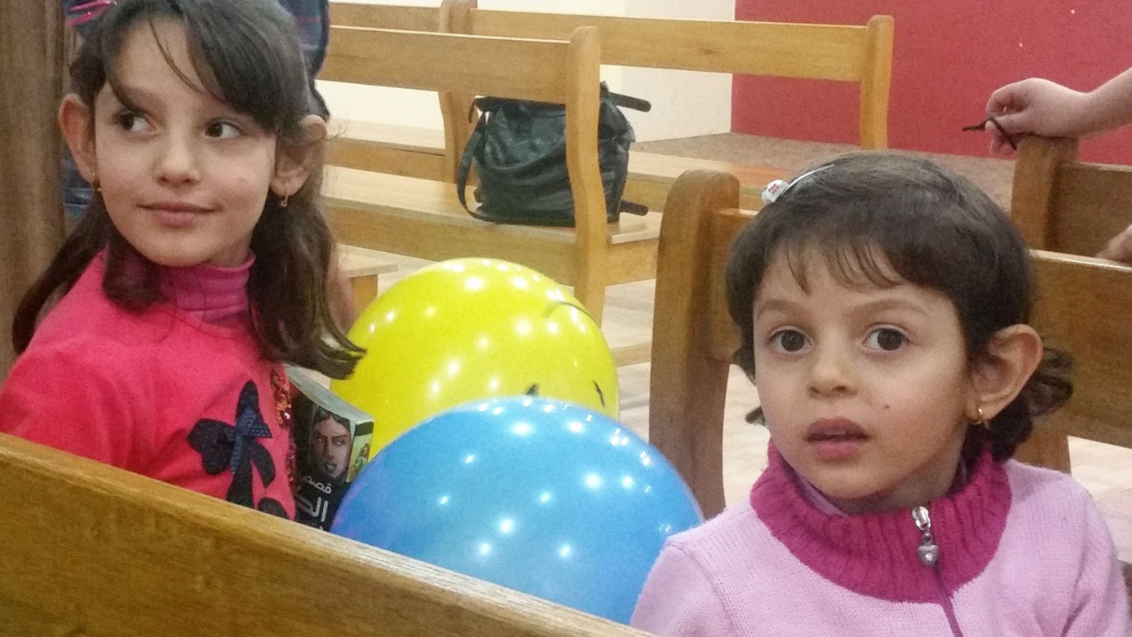 Two young girls attending a community outreach event with colorful balloons.