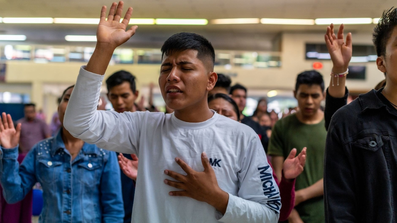Young man worshipping with raised hand during a Christian gathering.