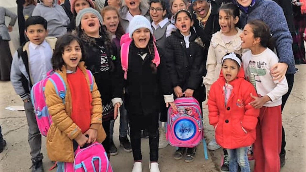 Children with colorful backpacks gathered during a Christian mission outreach.